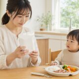 ポークビッツの表示を確認しながら幼児の食事を見守る日本人の母親