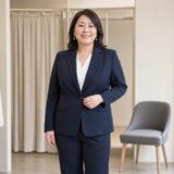 明るいフィッティングスペースでネイビースーツを着る40代ぽっちゃり女性